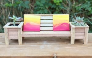 A miniature Cedar Bench that is holding two miniature paintings.